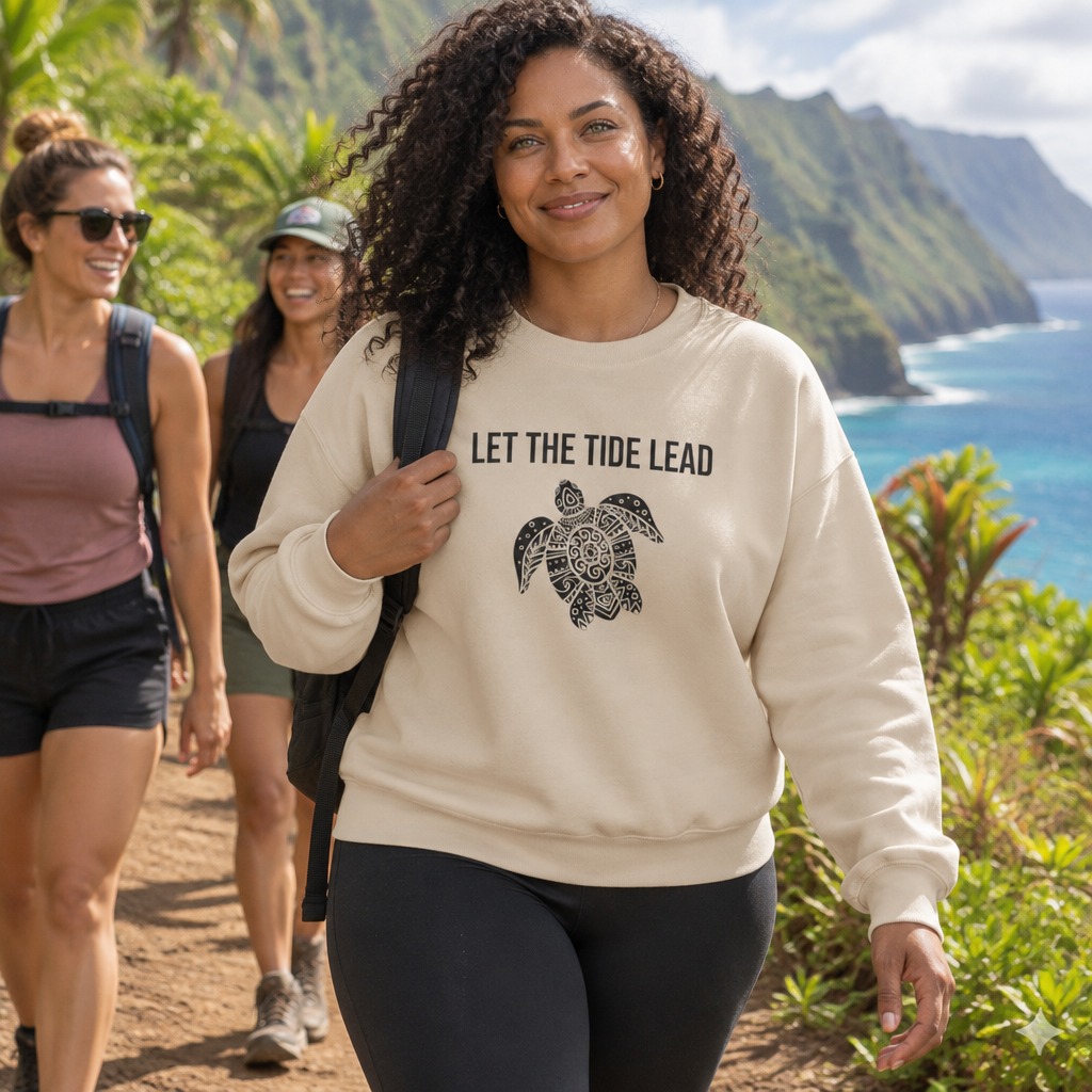 Woman hiking a coastal trail wearing the sand Let the Tide Lead turtle crewneck
