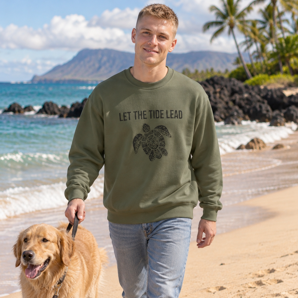 Man walking a golden retriever on the beach wearing the military green Let the Tide Lead turtle crewneck