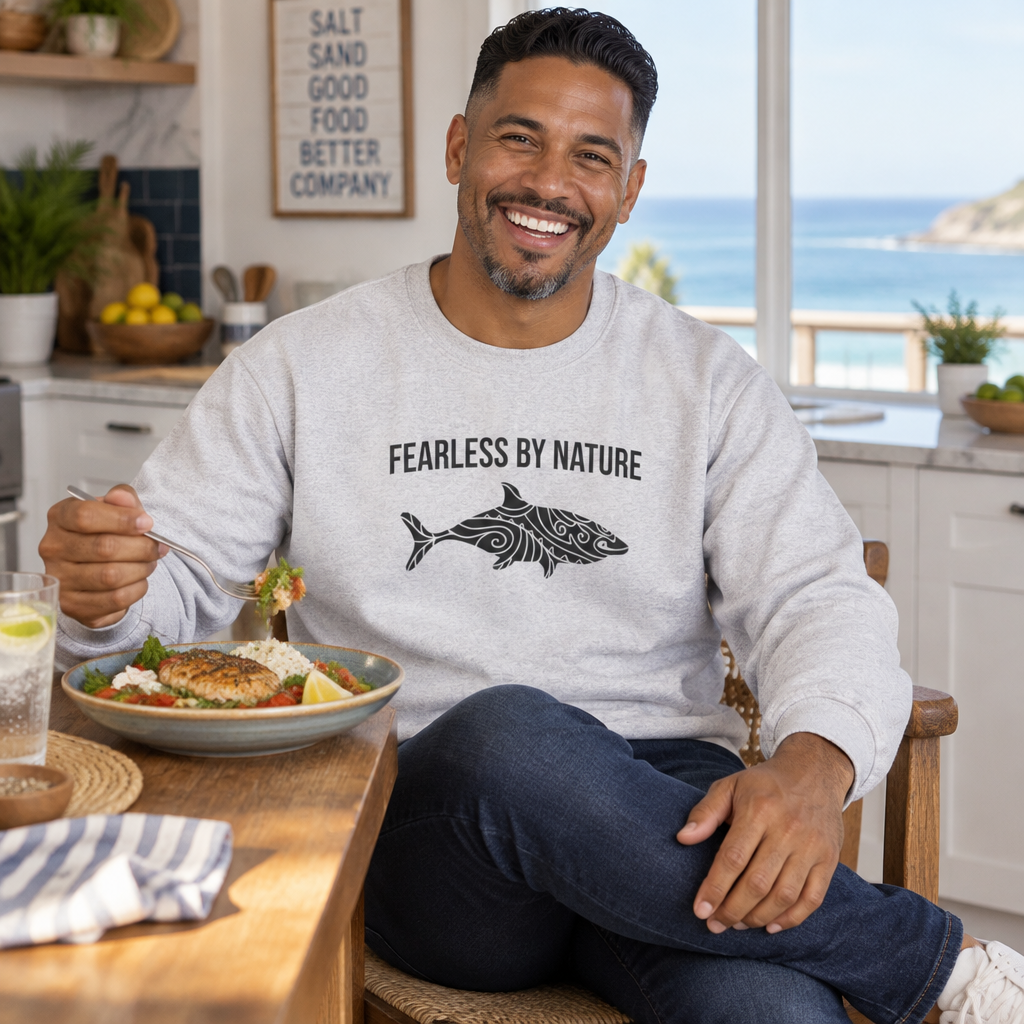 Man eating breakfast in a kitchen wearing the ash Fearless by Nature shark crewneck