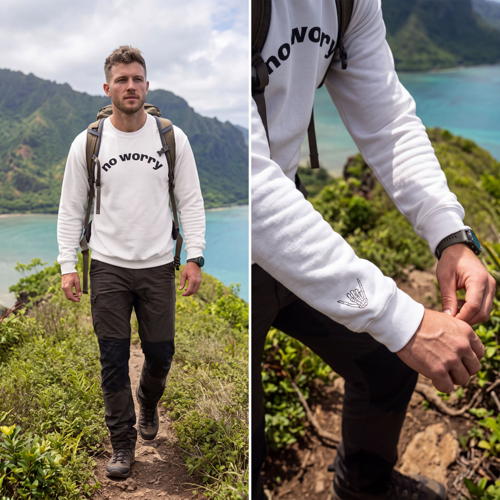 Man hiking a coastal trail wearing the white No Worry crewneck, with wrist shaka print detail