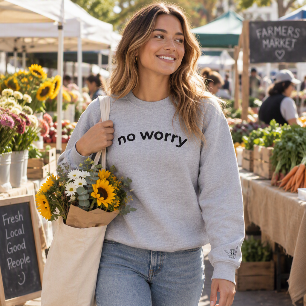 Woman holding sunflowers at a farmers market wearing the sport grey No Worry crewneck