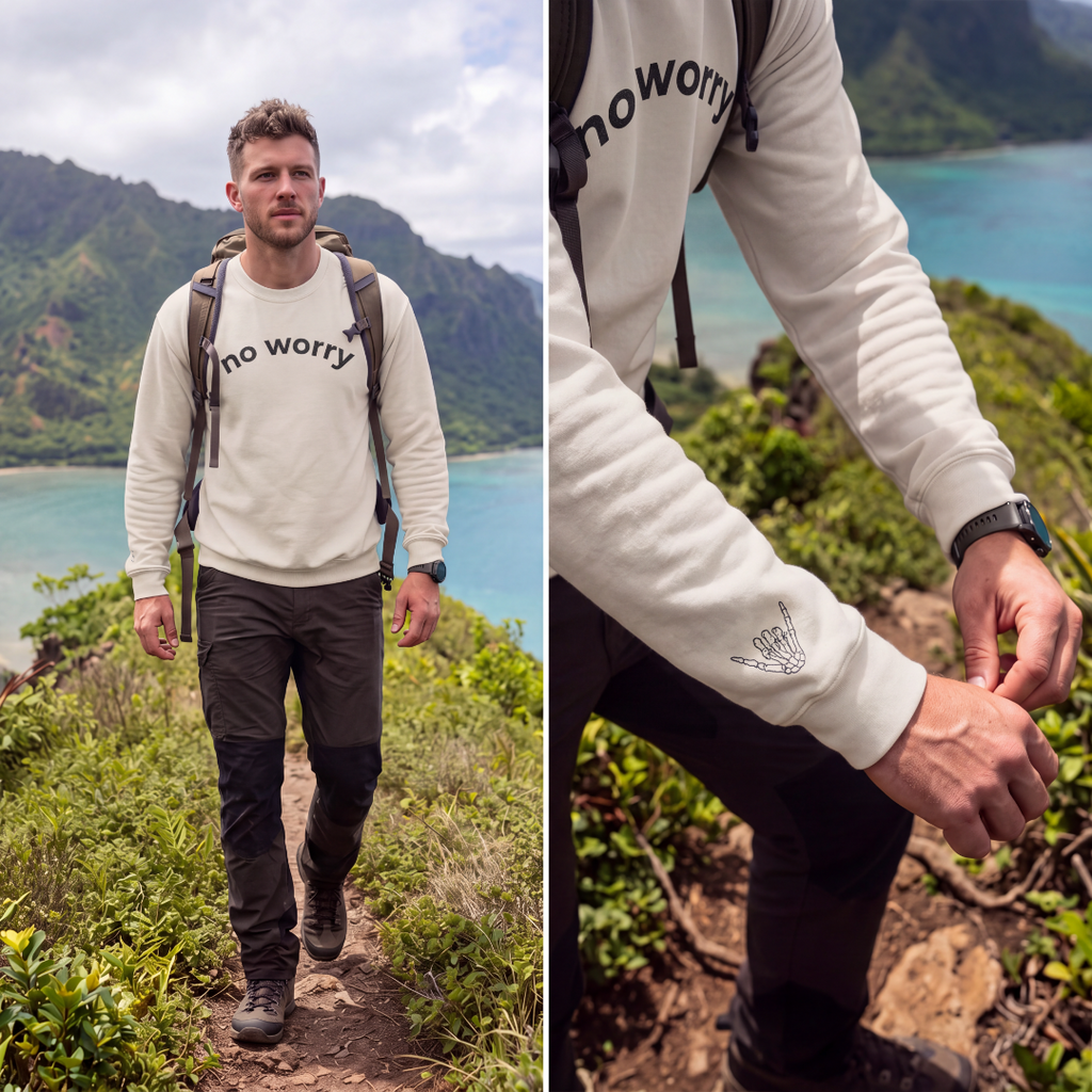 Man hiking a coastal trail wearing the sand No Worry crewneck, with wrist shaka print detail