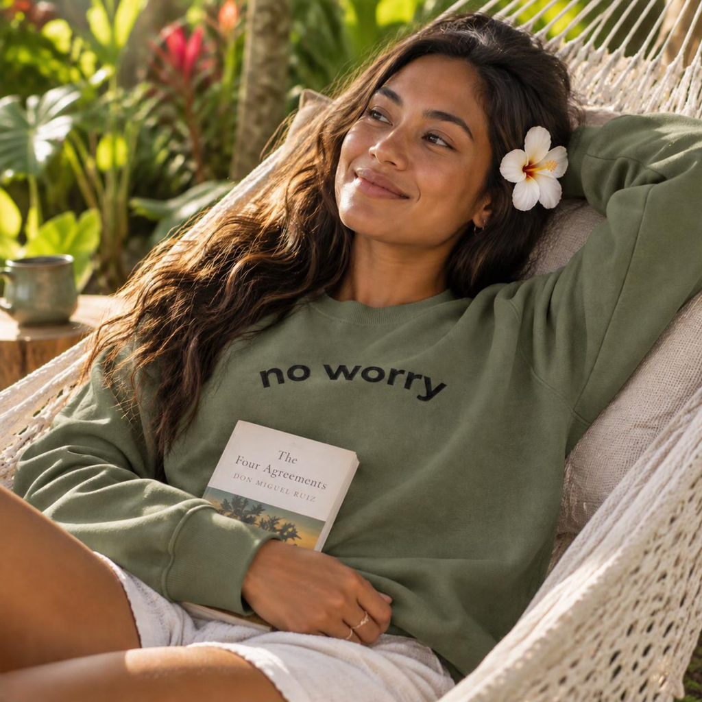 Woman relaxing in a hammock with a book wearing the military green No Worry crewneck