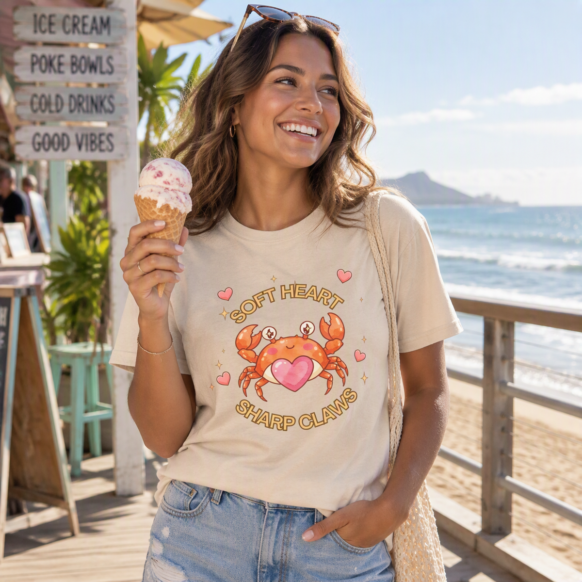 Woman holding an ice cream cone at the beach wearing the sand Soft Heart Sharp Claws crab tee