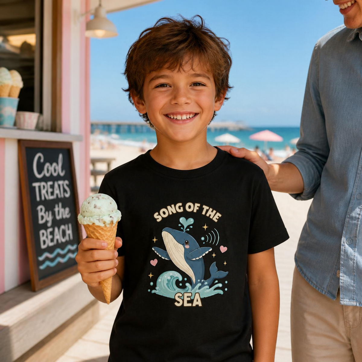 Boy holding an ice cream cone wearing the black Song of the Sea whale kids tee