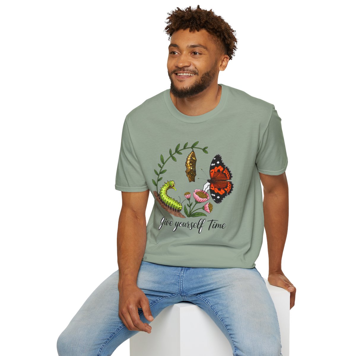 Man sitting wearing the sage Give Yourself Time butterfly transformation tee
